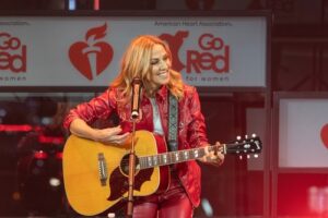 Sheryl Crow playing guitar for the article 10 Essential Rock Songs About Liars And Lying