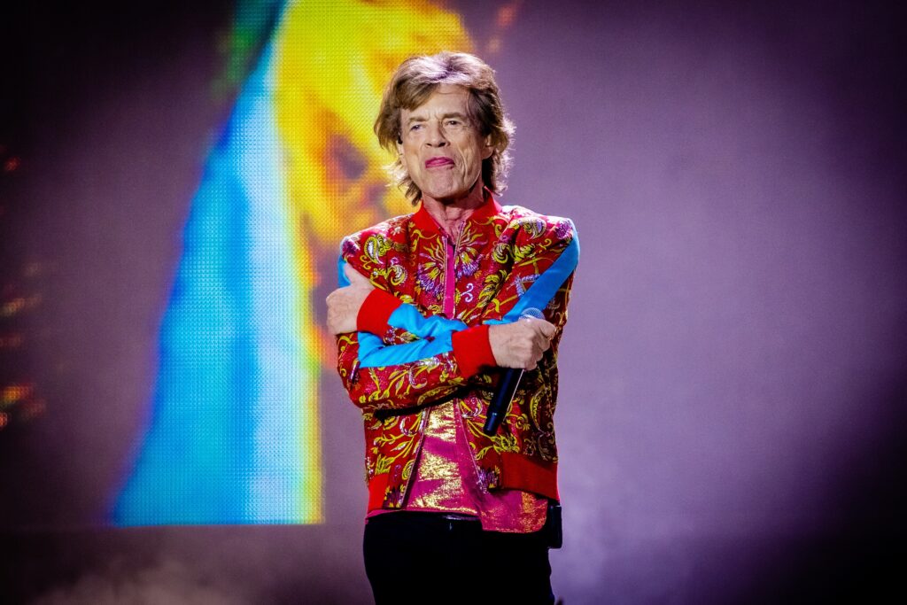 Picture of Mick Jagger standing on stage used to represent the article 10 Best Classic Rock Songs About Needing Help.